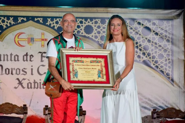 Imagen: Mavi Pérez entrega un cuadro de reconocimiento a César Rodríguez, Pregonero de las fiestas, en un escenario.