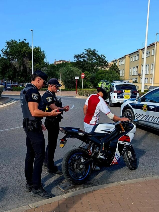 Imagen: Dos agentes de la Policía Local de Xàbia inspeccionan un ciclomotor y hablan con su conductor en un control.