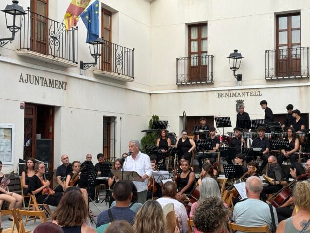 Imagen: Rafael Andarias hablando con micrófono en la plaza de Benimantell, con la orquesta detrás.
