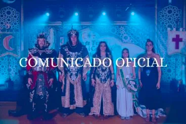 Representantes de la Junta de Festes de Moros i Cristians de Xàbia con trajes festeros en un escenario con el texto "COMUNICADO OFICIAL" superpuesto.