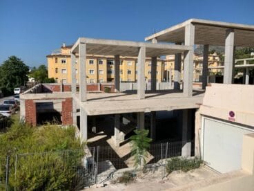 Vista de la estructura de hormigón inacabada del futuro Auditorio Municipal de Xàbia en un día soleado.