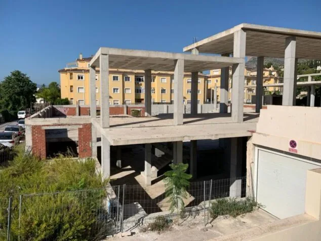 Imagen: Vista de la estructura de hormigón inacabada del futuro Auditorio Municipal de Xàbia en un día soleado.