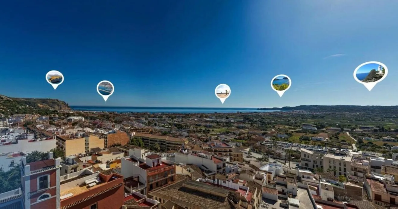 Vista aérea panorámica de la costa y el casco urbano de Xàbia con iconos de localización.