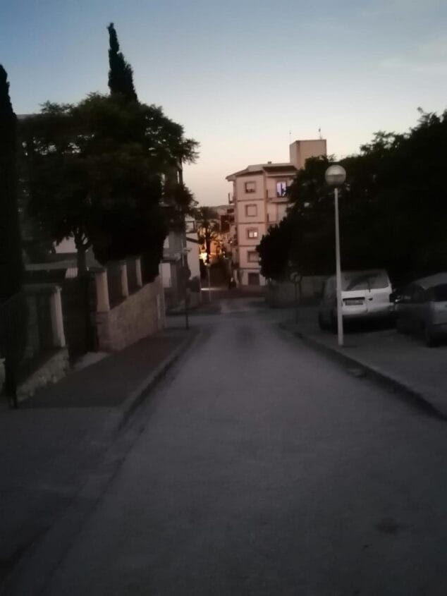 Imagen: Vista de una calle desierta en el centro histórico de Xàbia con poca luz y coches aparcados durante el eclipse.