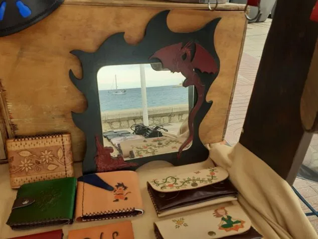 Puesto de artesanía con espejo y carteras de cuero en Jávea.