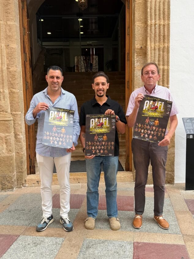 Imagen: Tres hombres posan frente a una puerta de piedra sosteniendo carteles del evento de boxeo 'I Memorial Ariel León Camargo' en Xàbia.