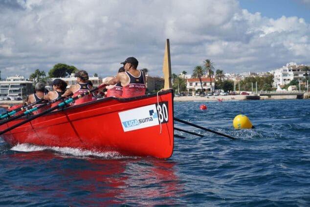 Imagen: Embarcación roja de remo del Club Náutico Oliva con varios remeros en el mar durante una competición en Jávea.