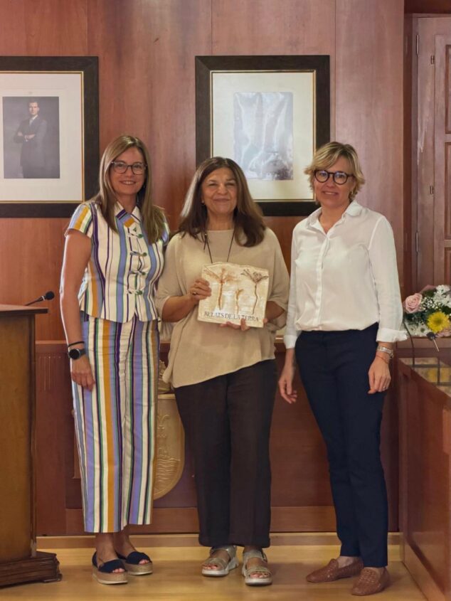 Tres mujeres posan durante la entrega del premio 'Relats de la Terra' a la ganadora, que sostiene el galardón.