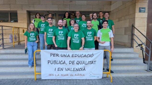Grupo de docentes del IES La Mar de Xàbia con camisetas verdes y una pancarta blanca reivindicativa frente a la entrada del instituto.