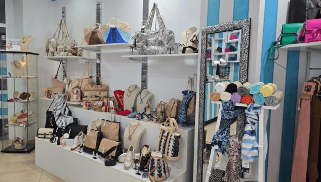 Imagen: Interior de una tienda de bolsos, zapatos y accesorios en Xàbia con productos expuestos en estanterías y expositores.